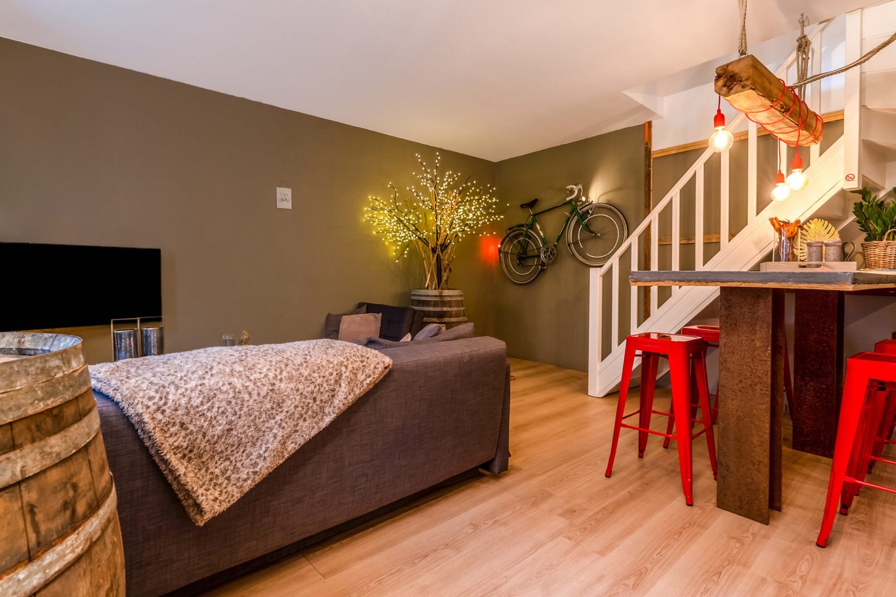 Woonkamer met bank, bar en racefiets aan de muur